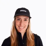 Gorra negra de trail running con estampado frontal reflectante, elástico en 4 direcciones, panel de malla transpirable, ajuste trasero, visera plana y estructura ligera y ajustable.