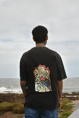 Remera color arena de algodón con cuello redondo y mangas cortas. Estampado frontal con tres hongos rojos y la palabra "Tuya" debajo.