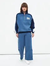 Pantalón deportivo azul piedra de corte evasé con bolsillos laterales tipo cargo.