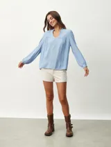 Blusa blanca de manga larga con escote en V y textura arrugada.