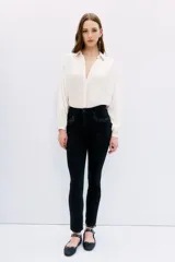 Jean slim tiro medio-alto, color negro, calce al cuerpo, pierna semi-recta y detalle de hotfix en bolsillos.