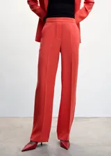 Pantalón de traje de corte wideleg color coral, de tejido fluido con forro interior y elástico en la parte posterior de la cintura. Presenta dos bolsillos laterales y cierre oculto de botón, gancho y cremallera.