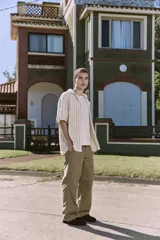 Camisa de manga corta a rayas verticales color crudo y verde, con cuello resort, corte holgado y cierre frontal con botones.