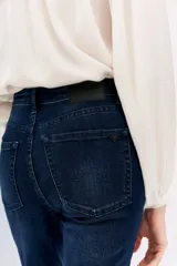 Pantalón de jean azul oscuro, corte slim, tiro alto y bolsillos delanteros y traseros.