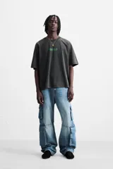 Camiseta gris oscuro con efecto lavado, cuello redondo, manga corta y estampado de textos combinados en verde neón en el delantero y la espalda.