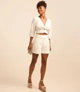 Blusa cropped de laise blanca con escote en pico, detalle torcido en el busto y manga corta abullonada.