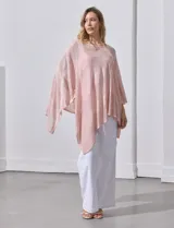 Poncho blanco de tejido calado con lurex, terminación asimétrica y cuello redondo.