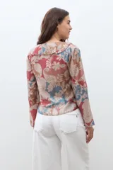 Blusa de manga larga con escote en V y volados en el frente. Presenta un estampado paisley en tonos rojo, azul y beige.