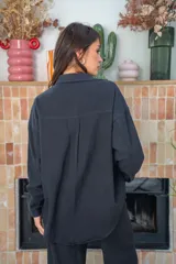 Camisa blanca de algodón con cuello clásico, cierre frontal con botones metálicos a presión, dos bolsillos de parche en el pecho y apliques de brillos en la parte delantera.