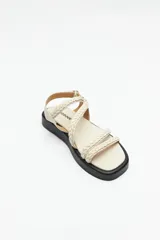 Sandalias color beige con plataforma negra, tiras trenzadas y ajuste con velcro en el talón.