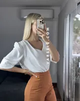 Blusa negra de crepé de lino con escote en V, mangas 3/4 con hombreras y detalle fruncido en los hombros. Se ata en la espalda con tiritas.