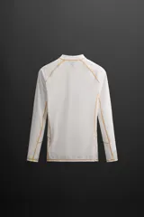 Camiseta de surf blanca de manga larga, confeccionada en tejido técnico elástico con protección solar UPF40+. Presenta cuello alto, corte ajustado y costuras planas. Logo estampado en la manga.