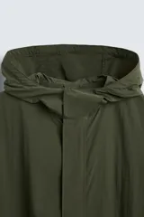 Parka verde militar de tejido técnico ligero, corte oversize, cuello alto con capucha ajustable, manga larga con puños elásticos, cintura ajustable con cordón interno, bolsillos con solapa, bajo asimétrico con abertura trasera ajustable y cierre frontal con cremallera oculta y botones a presión.