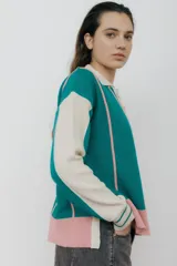 Sweater de punto color verde esmeralda, con cuello polo, mangas largas color crema y detalles en rosa.