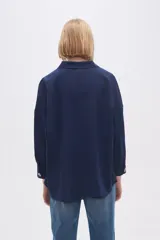 Blusa blanca holgada de poliéster con cuello camisero y mangas largas.