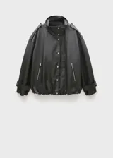 Anorak negro oversize con cuello alto, cierre frontal con botones y cremallera oculta, dos bolsillos laterales con cremallera, mangas largas con puños abotonados y charreteras en los hombros.