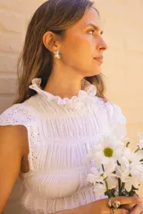 Blusa blanca de algodón con textura fruncida y detalles de broderie en cuello, mangas y ruedo.