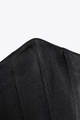 Top bustier negro de satén con escote corazón y hombros descubiertos. Cierre trasero con cremallera metálica.