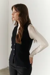 Chaleco gris de tejido de punto con cuello en V, cierre frontal con botones y bolsillos delanteros.