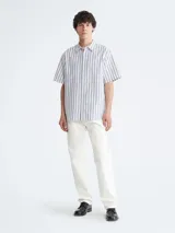 Camisa de manga corta con rayas verticales azules y blancas, cuello clásico y cierre con botones.