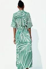 Vestido midi camisero con estampado de rayas verdes y blancas, cuello camisero, botonadura frontal, mangas cortas raglán, elástico en la cintura y cinturón extraíble para atar.