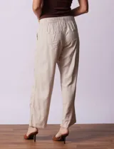 Pantalón largo de lino y rayón a rayas verticales grises y blancas. Tiene pretina elastizada con lazo de ajuste, bolsillos delanteros y traseros.