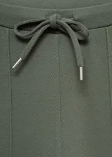 Pantalón jogger verde militar de piqué con cintura elástica ajustable con cordón, bolsillos laterales y costuras decorativas.