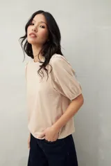 Remera color beige de mangas cortas abullonadas con elástico en la terminación.