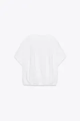 Camiseta blanca de algodón con cuello redondo, mangas cortas y bajo asimétrico ajustable con lazadas.