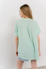 Blusa color verde agua de lino, con cuello mao y escote en V abotonado.