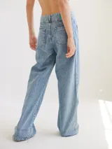 Pantalón negro de tiro medio alto, corte palazzo, con bolsillos delanteros y traseros.