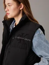 Chaleco puffer negro Calvin Klein Jeans con logo bordado en el pecho, cuello alto, cierre frontal con botones a presión y bolsillos laterales.