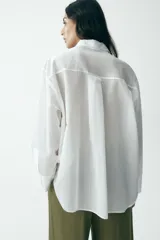 Camisa blanca con rayas verticales, cuello solapa, manga larga y cierre frontal con botones.