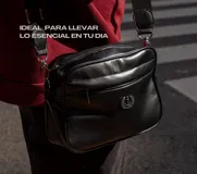 Bandolera negra de cuero sintético con correa ancha ajustable y desmontable. Cuenta con cierre superior, bolsillo frontal con tiracierre customizado, forro interno y cuatro bolsillos en total (dos exteriores y dos interiores).