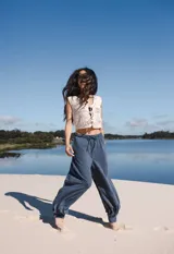 Pantalón de lino azul con tiro medio, elástico y lazo en la cintura, y puño con botón de nácar en el tobillo.