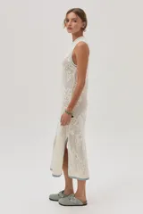 Vestido midi tejido de punto color crudo, con calados florales, calce recto, tajos laterales y detalles en celeste en cuello, sisas y ruedo.