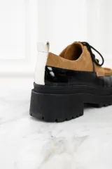 Mocasín abotinado con capellada combinada en cuero color marrón y charol negro.