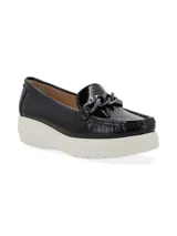 Mocasín de cuero charol negro con plataforma blanca y detalle de hebilla metálica plateada en el empeine.