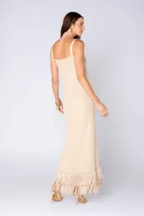 Vestido largo color beige con textura geométrica, breteles finos y escote con nudo. Posee flecos en el ruedo.