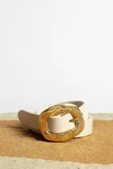 Cinturón color crema con hebilla cuadrada dorada con diseño irregular.