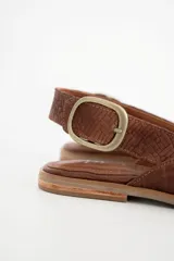 Zapato chata de cuero color marrón con textura tejida y hebilla dorada.