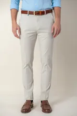 Pantalón de vestir color gris claro, de corte slim fit, con bolsillos laterales y traseros. Se ajusta a la cintura con cinturón de cuero marrón.