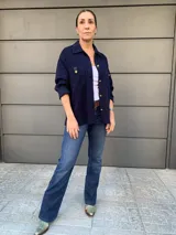 Camisa azul marino de tejido de punto en algodón, con cuello camisero, cierre frontal con botones dorados, bolsillo de parche con solapa de cuero sintético y mangas largas.