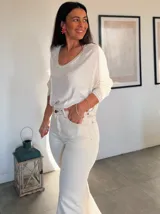 Blusa color crema con lentejuelas, de mangas largas y escote redondo.