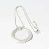 Collar plateado con dije circular irregular.