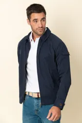 Campera color beige con cierre frontal, cuello camisero, bolsillos laterales y elástico en la cintura. Detalle de bolsillo en la manga izquierda.