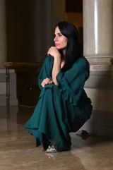 Vestido largo de fiesta color verde oscuro, con mangas acampanadas y falda con volados en cascada. Incluye clutch plateado.