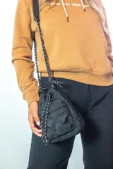 Bandolera negra de nylon con diseño capitoneado, forma de bolsa con ajuste de cordón y correa de hombro de cinta gruesa.