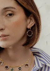 Par de aros colgantes con dije circular de resina con glitter multicolor y borde de strass. El arito es de acero quirúrgico dorado.