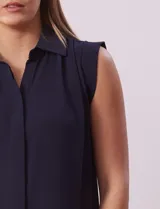Blusa negra de gasa marca Tahari, con cuello a la base con solapa, abertura central con botones ocultos y detalle plisado en hombros.